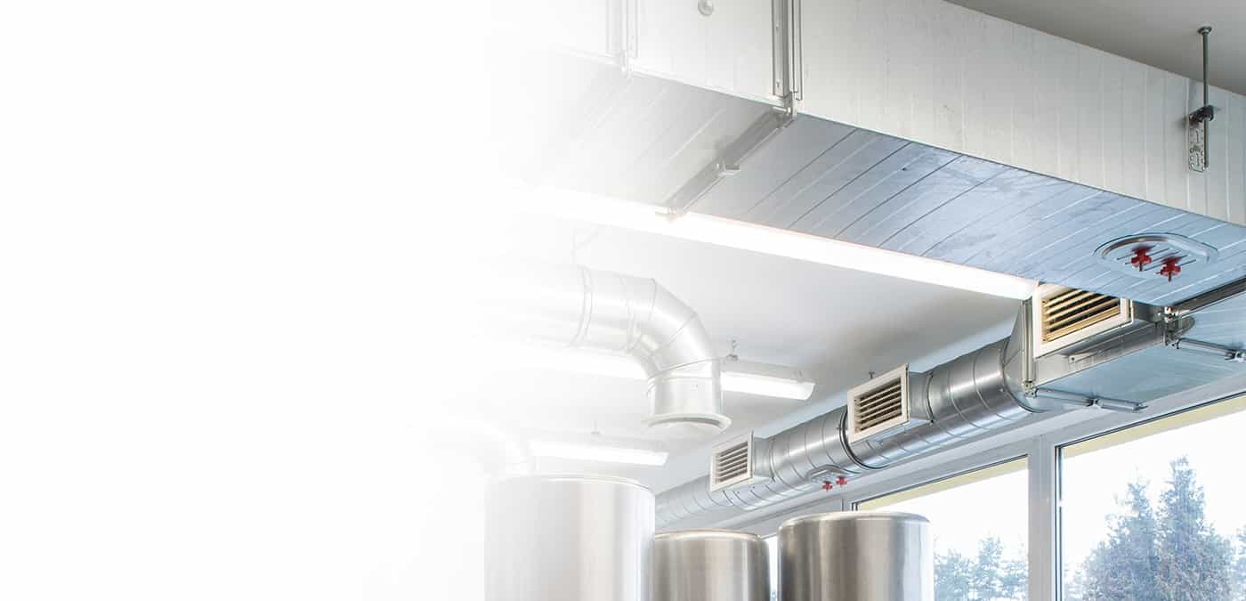 Sheet metal supply ducts and diffusers running along the ceiling of a commercial building